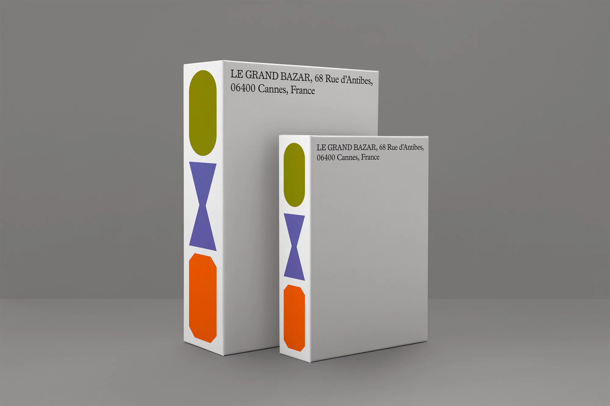 Two rectangular product boxes with geometric shapes and brand text, set against a grey background in a studio lighting setup.