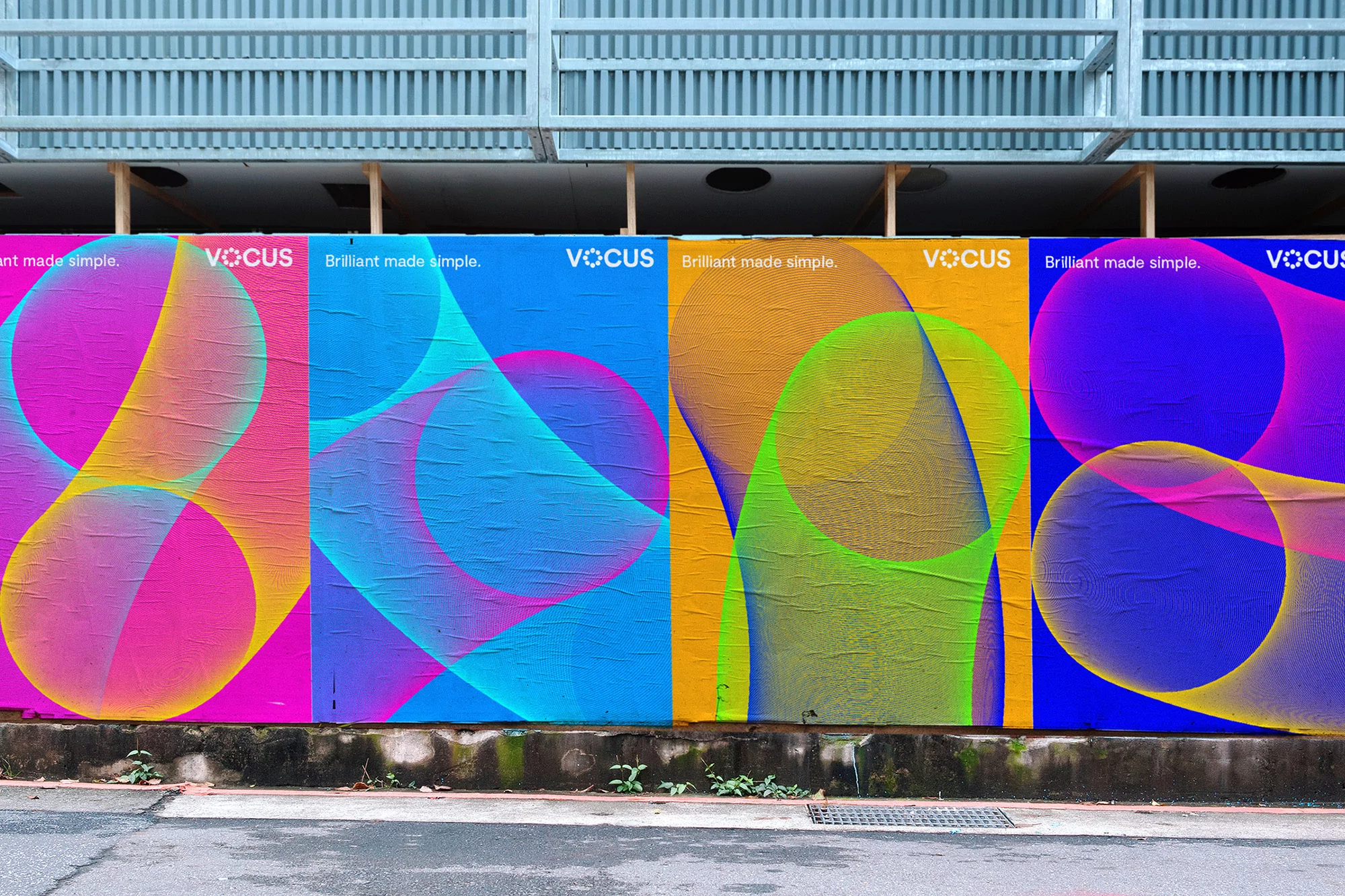 Outdoor banner ads for Vocus featuring colorful abstract designs, attached to a wall, and located along the street level.