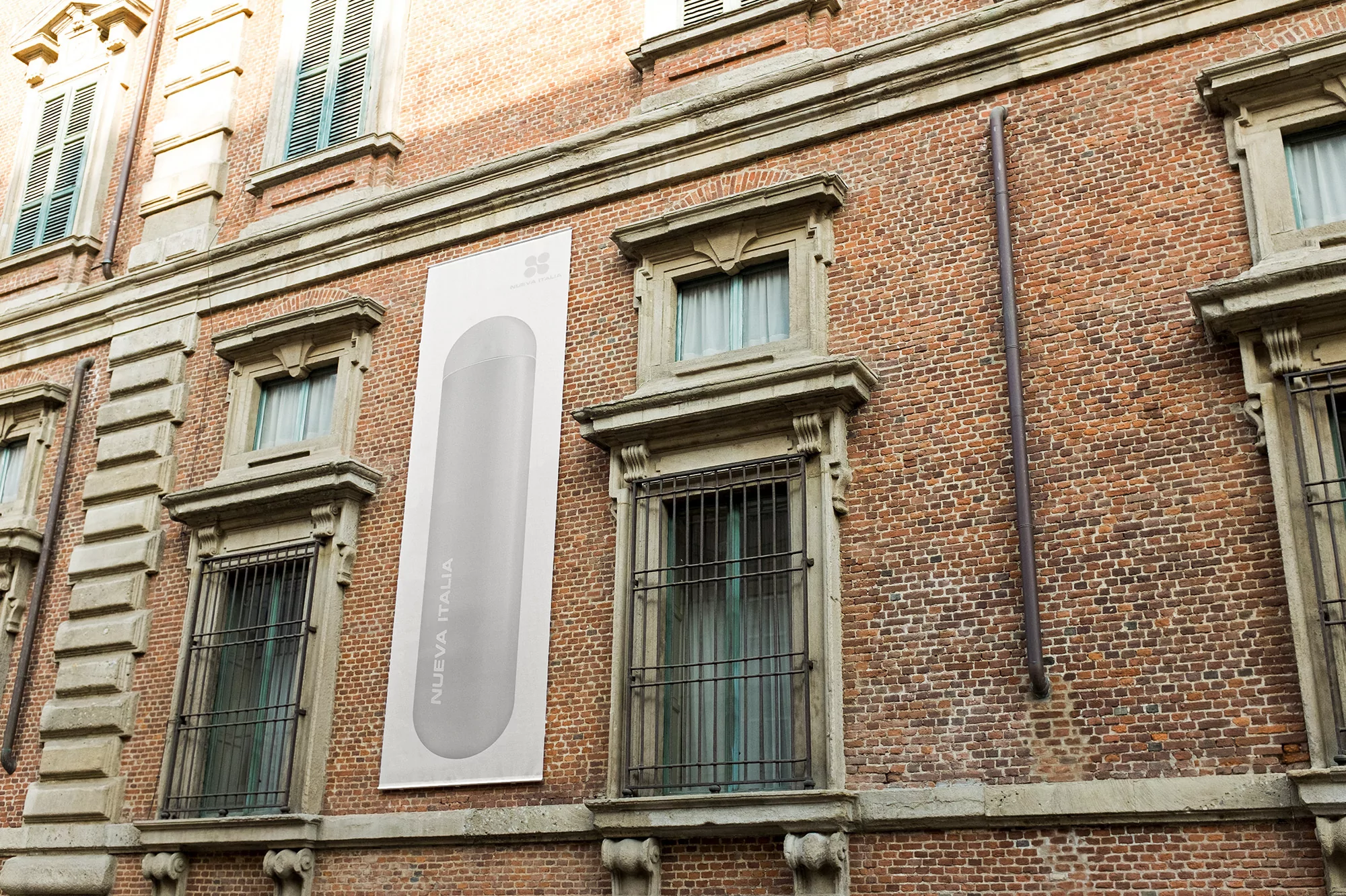 Exterior of brick building featuring an advertisement banner for 'Nuova Italia' and multiple window frames with classic architectural details.
