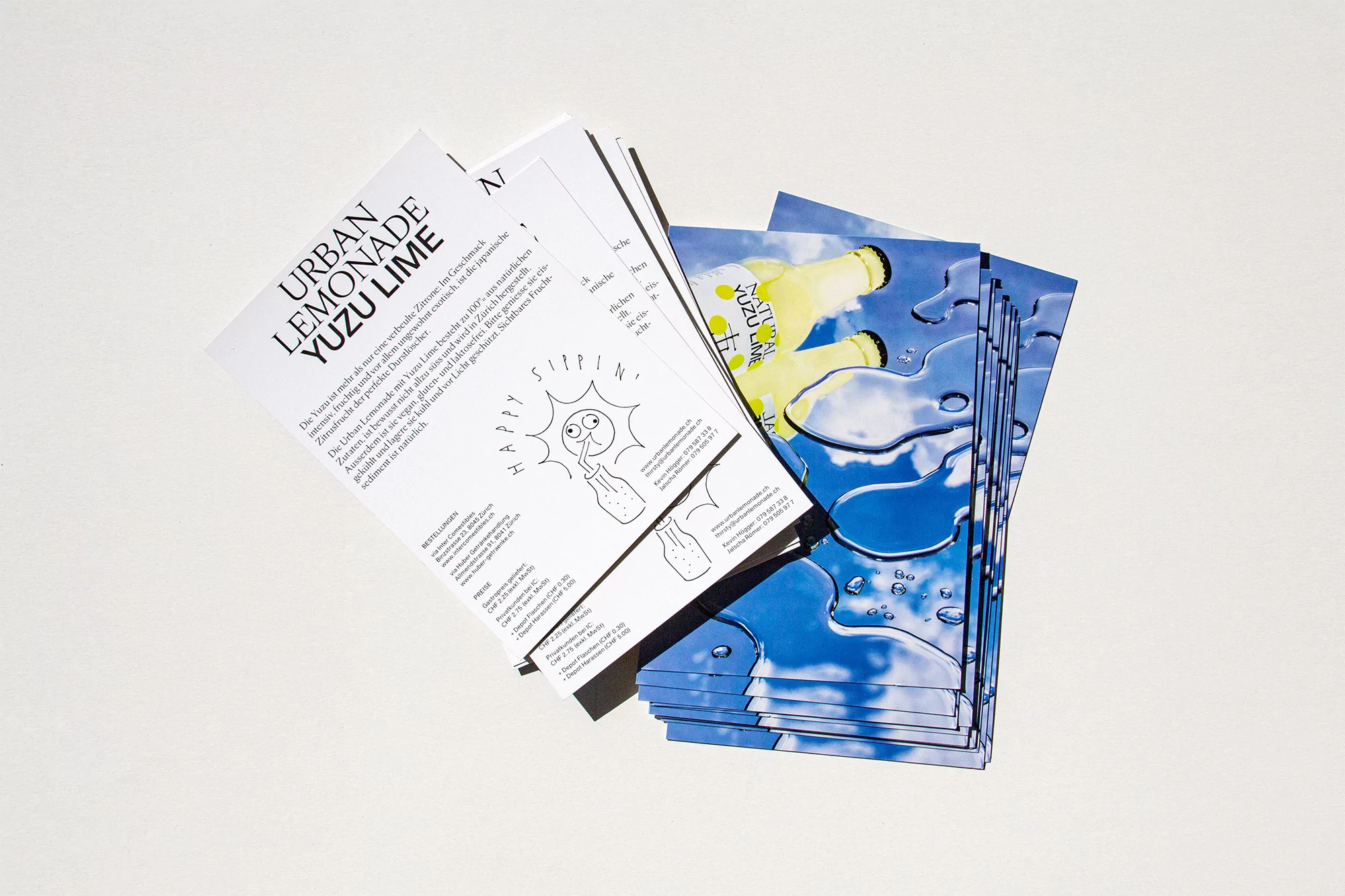 Promotional material showcasing Urban Lemonade Yuzu Lime: flyers with product info, vibrant sky-themed cards, displayed against a white backdrop.