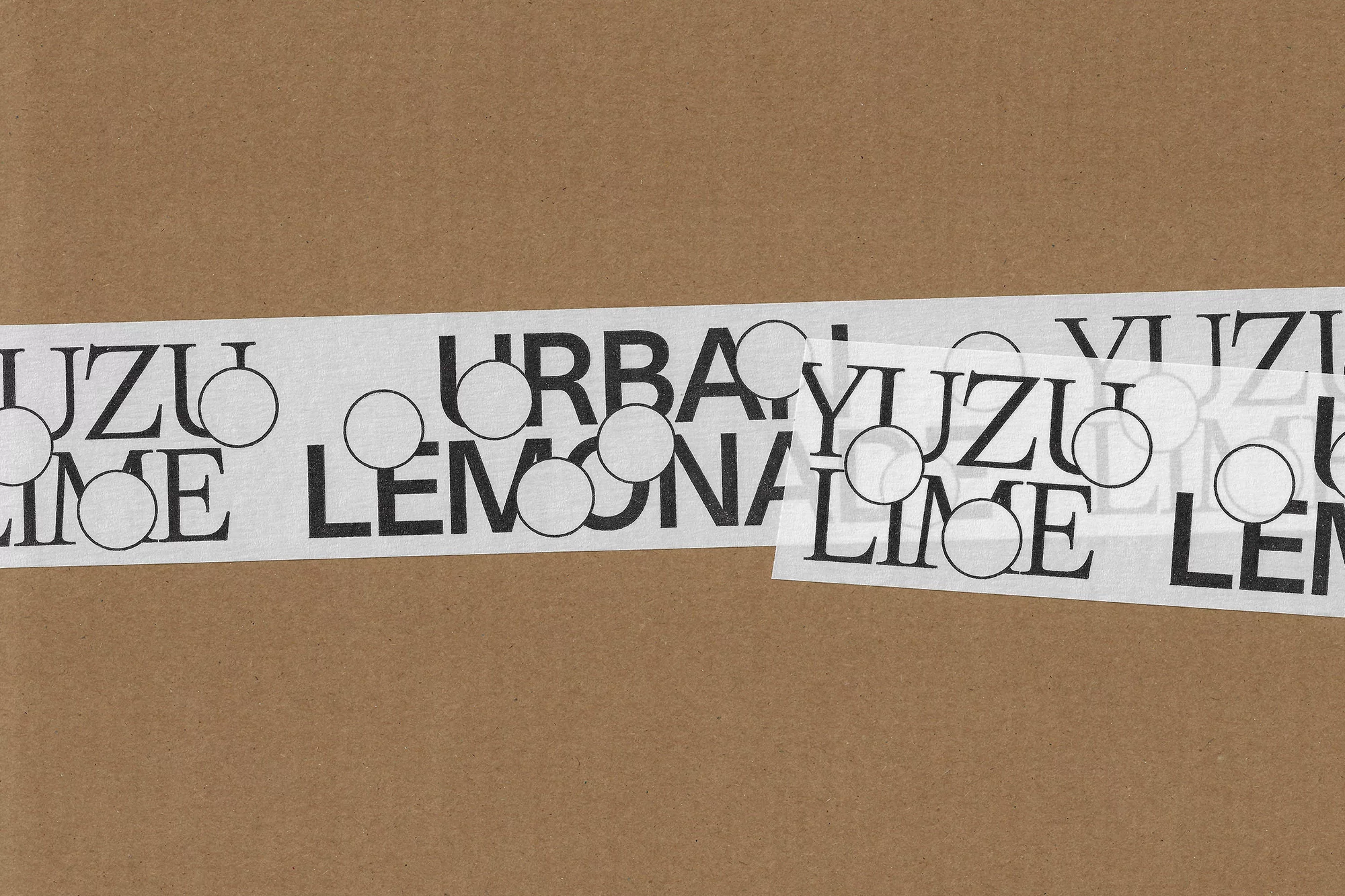 Promotional image featuring a piece of cardboard with a white tape on it, the tape has black lettering and round transparent stickers.