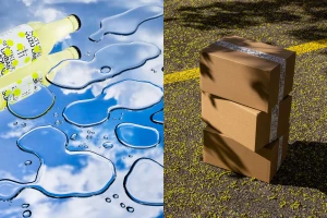 Split view of water puddles reflecting a cloudy blue sky next to a stack of three cardboard shipping boxes on asphalt.