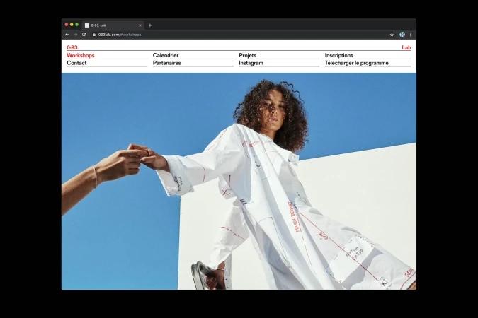 Fashionable woman in oversized print shirt with hands holding in the background, against blue sky, as shown on 0-93 Lab webpage.