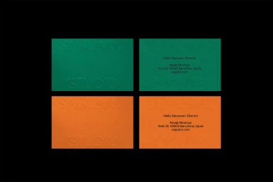 Four rectangular business cards in green and orange featuring embossed Saguaro Studio typography against a black background.