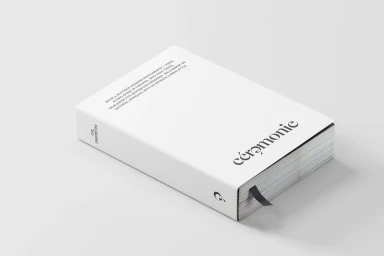 White book with black typography and a black ribbon bookmark on a light grey background