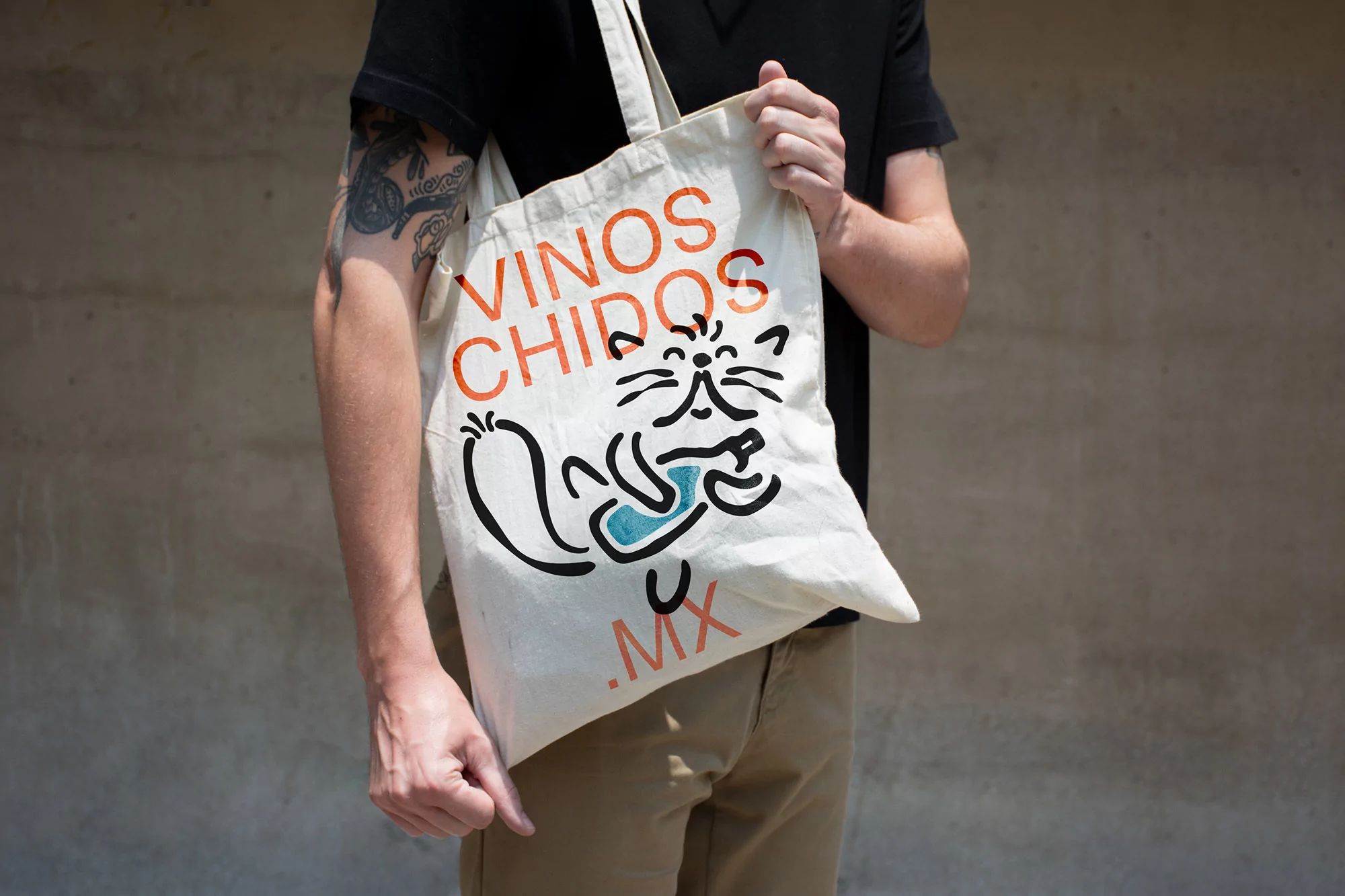 Adult holding a tote bag with text and a cartoon cat design against a neutral background, showcasing a casual and artistic style.