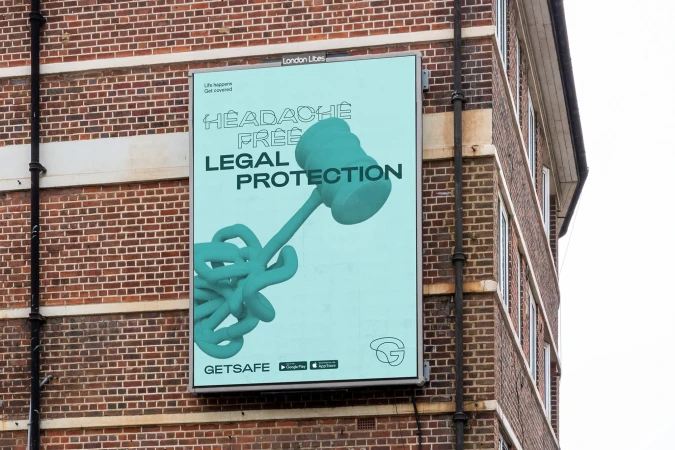 Outdoor billboard ad for legal protection, featuring a gavel tangled in cords, set against a brick building in an urban environment.