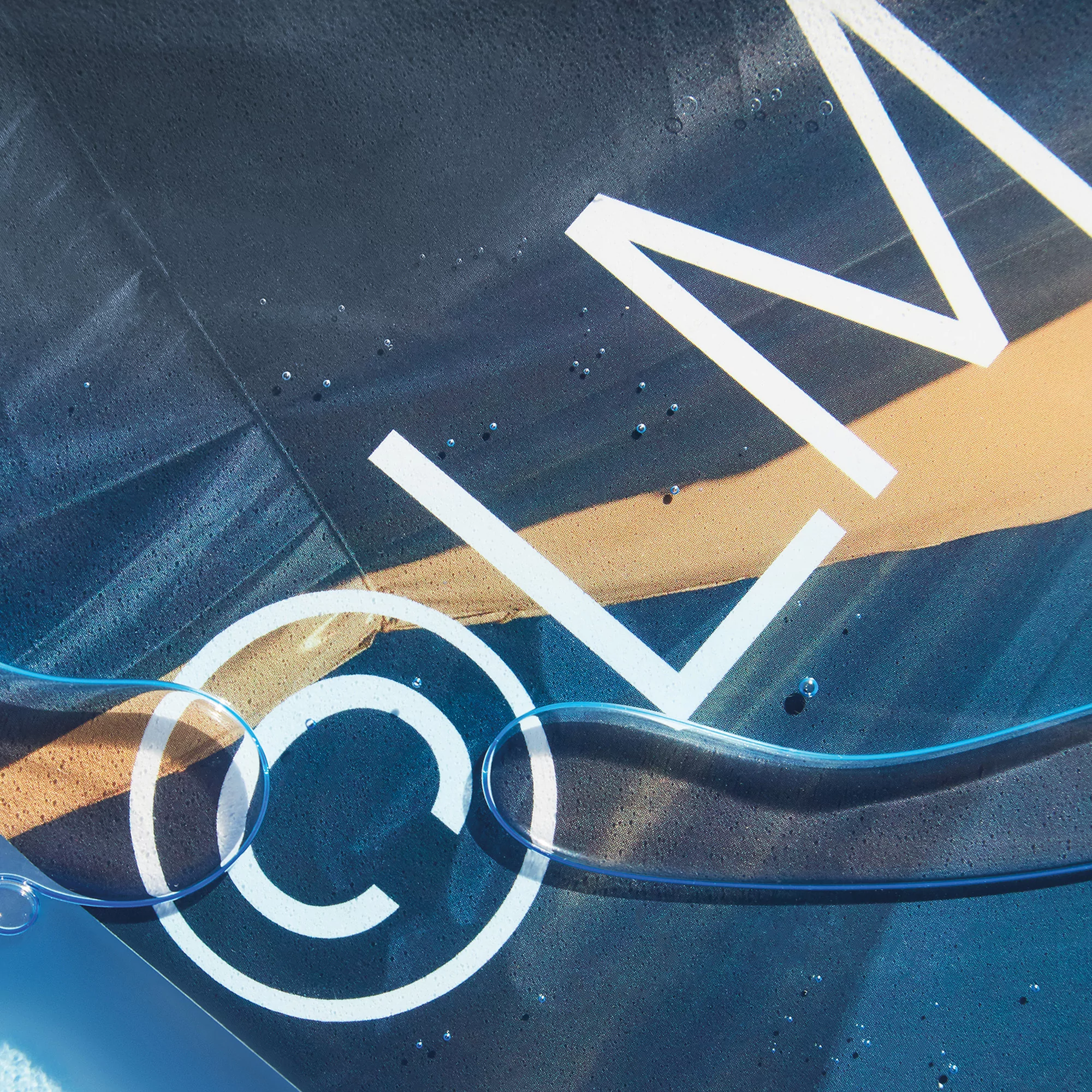 Abstract product shot featuring transparent tubing and water droplets against a dark blue and brown textured backdrop with white lettering.