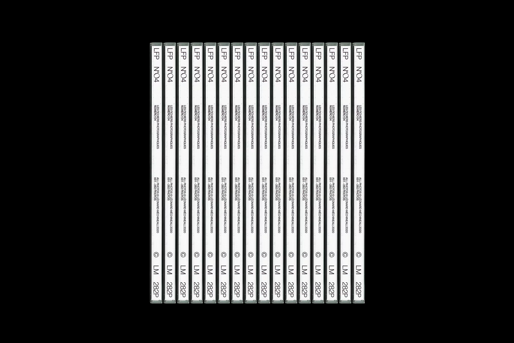 Multiple identical white labeled cassettes are aligned in rows on a black background, creating a pattern effect with vintage media.