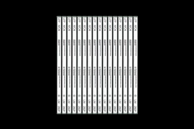 Multiple identical white labeled cassettes are aligned in rows on a black background, creating a pattern effect with vintage media.