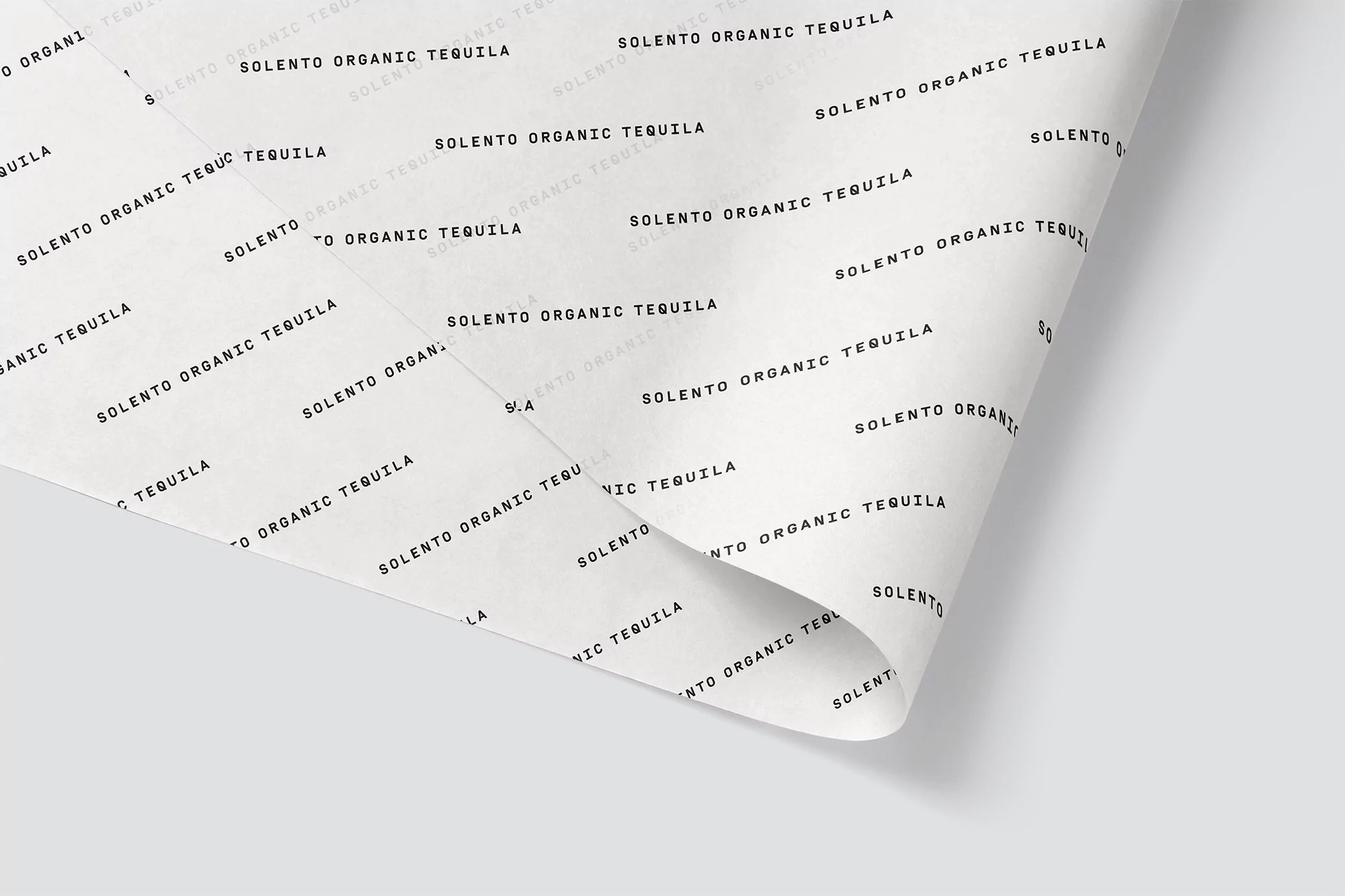 Printed paper with 'Solento Organic Tequila' text in black on a white background. Simple tequila advertisement backdrop for food and beverage.