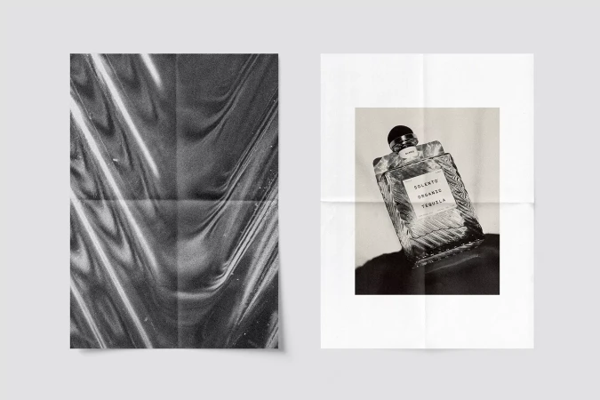 Monochromatic advertisement for Solento Organic Tequila features a product bottle on a poster with a textured plastic-wrapped poster.
