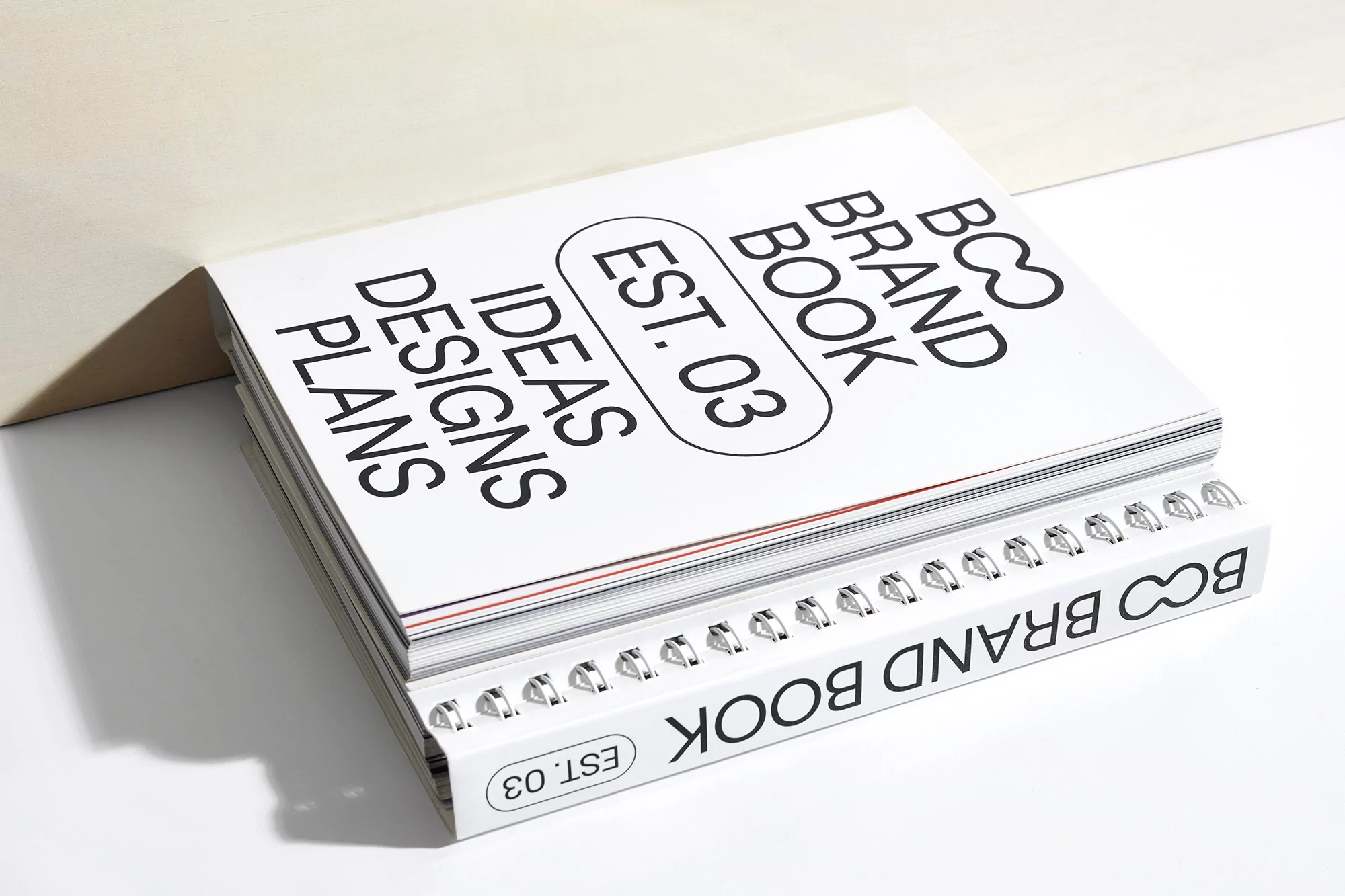 Two BCO brand books are stacked on a white surface with minimalist design, showcasing a focus on ideas, design, and plans in a studio setting.