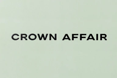 The black typographic brand logo Crown Affair centered against a solid pale sage green textured background surface.