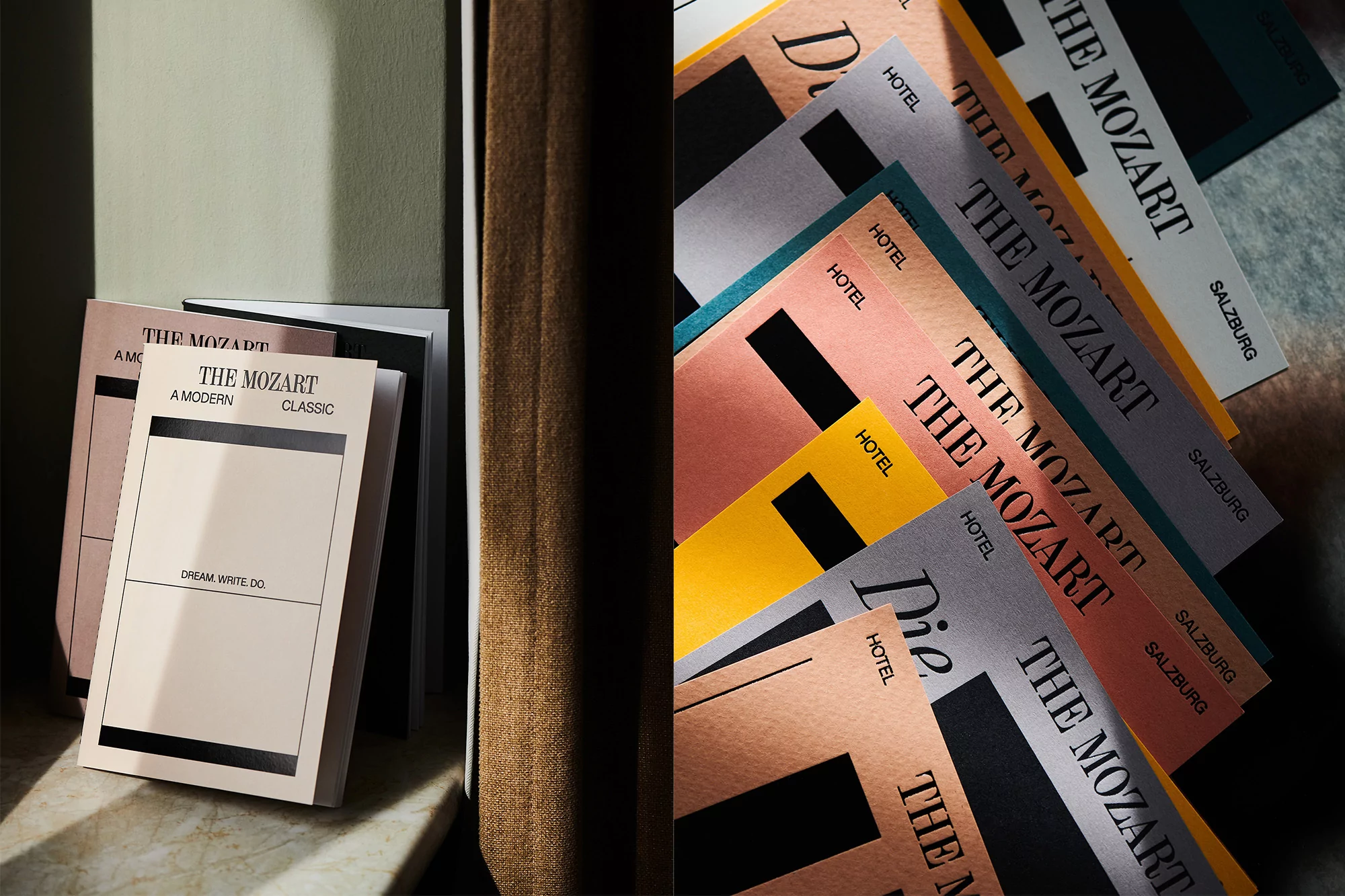 Close-up of hotel stationery in various colors stacked and scattered on a surface, featuring 'The Mozart Hotel Salzburg' branding.