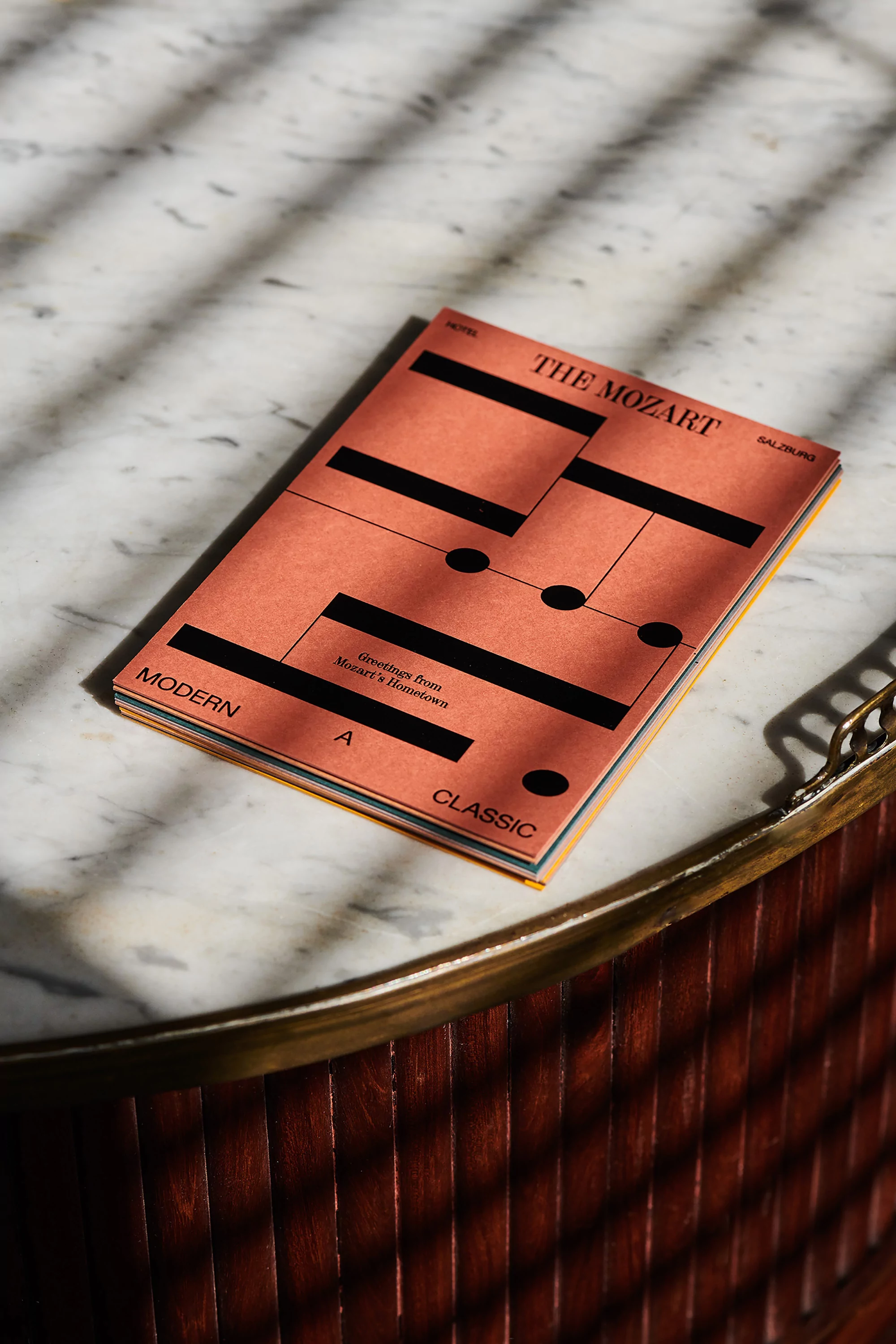 Sheet music book with abstract graphic notation on marble table with decorative wood border in bright, soft window light.