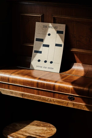 Sheet music for The Mozart lounge, bar and bistro rests atop a wood piano, illuminated by a beam of natural light in an indoor setting.