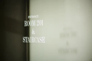 Signage on frosted glass reading Entrance Room 201 and Staircase in soft interior light