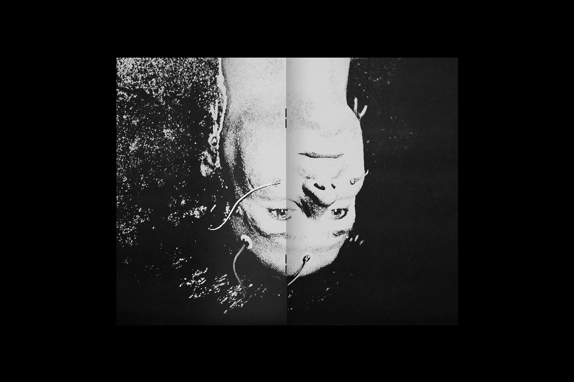 Monochrome graphic design featuring an inverted face with exposed wires on a textured black background.