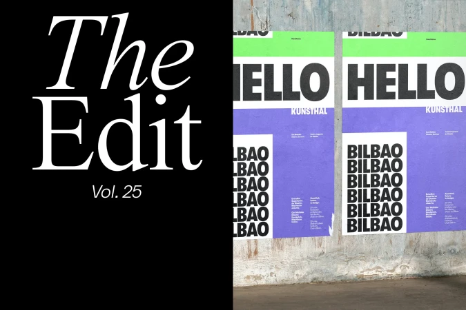 Two posters with graphic text and purple design are affixed to a textured concrete wall against a black background, art installation.