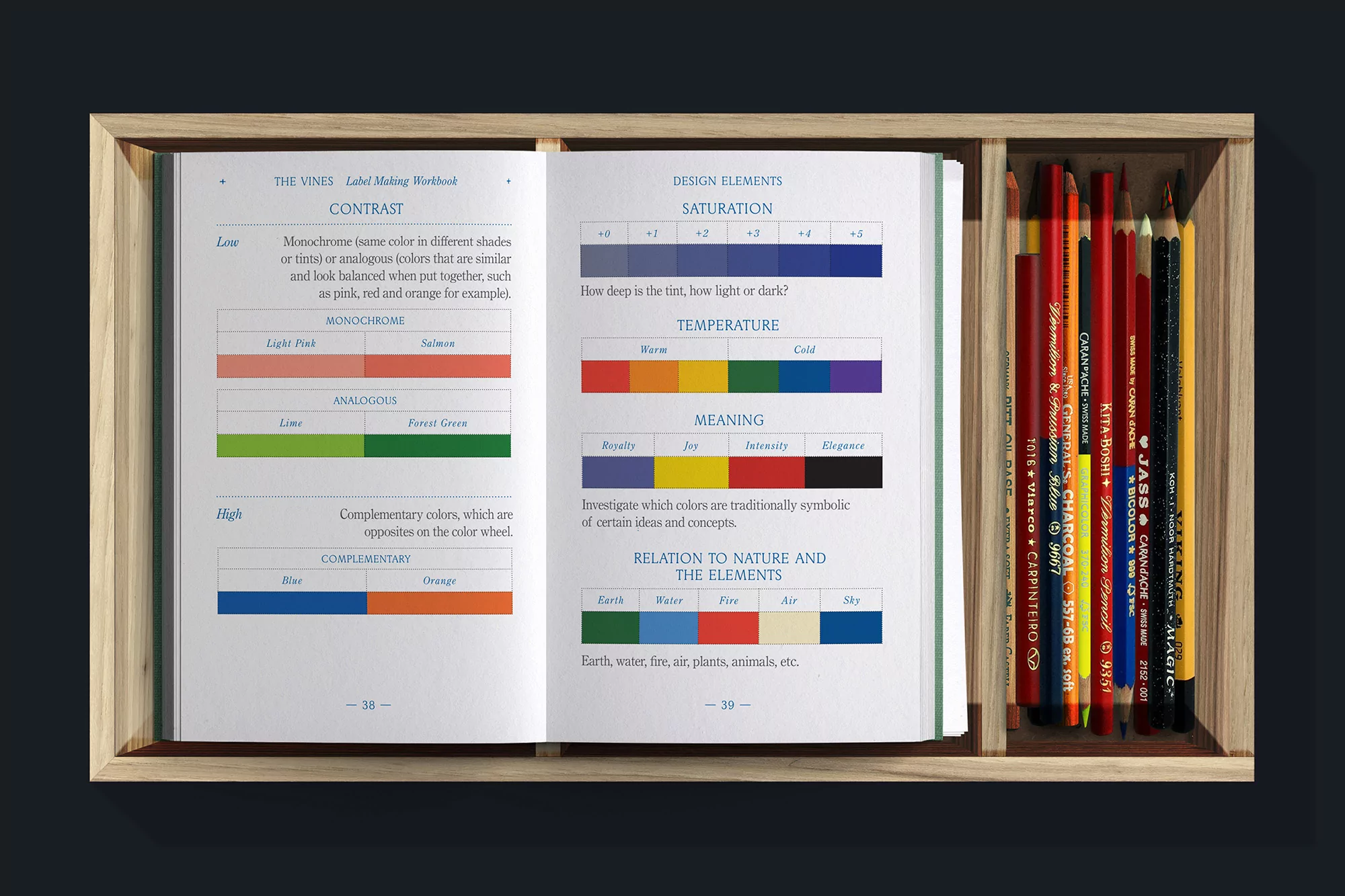 Open book showing color palettes and color theory, with pencils in a wooden tray. Focus on color schemes and educational content.