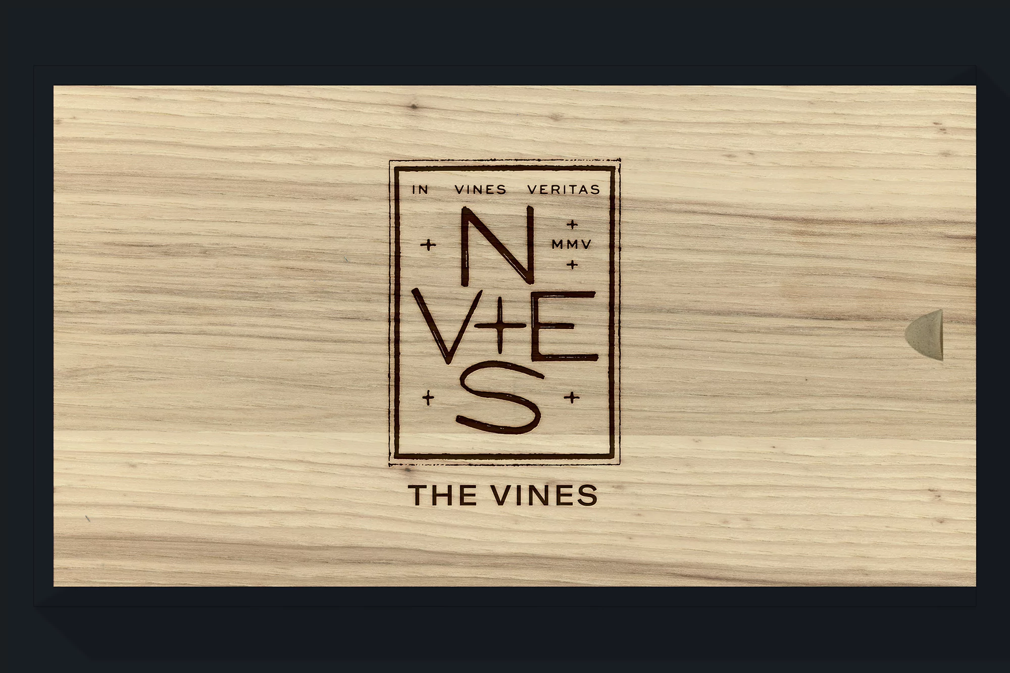 Wooden box with the words 'In Vines Veritas' and 'The Vines' engraved on the surface, presented in a studio setting.