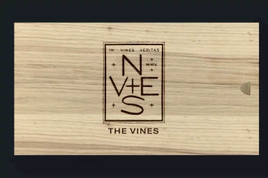 Branded wooden wine box featuring a rectangular logo stamp and the text THE VINES on a light wood grain texture