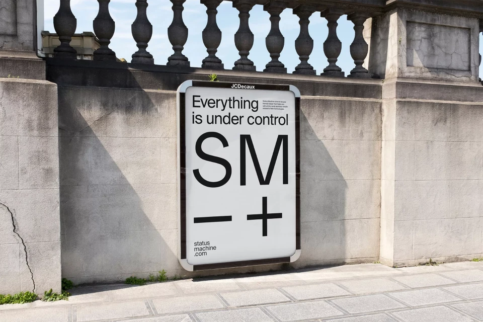 Outdoor billboard on a stone wall featuring the text 'Everything is under control SM -+' with the website statusmachine.com.