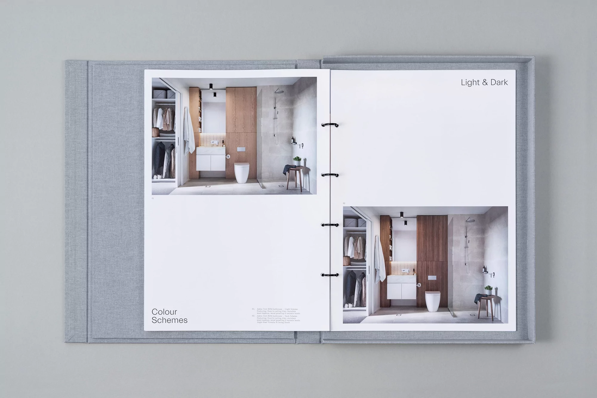 Open binder book featuring bathroom interior designs with toilet, sink, and shower stall in both light and dark color schemes.