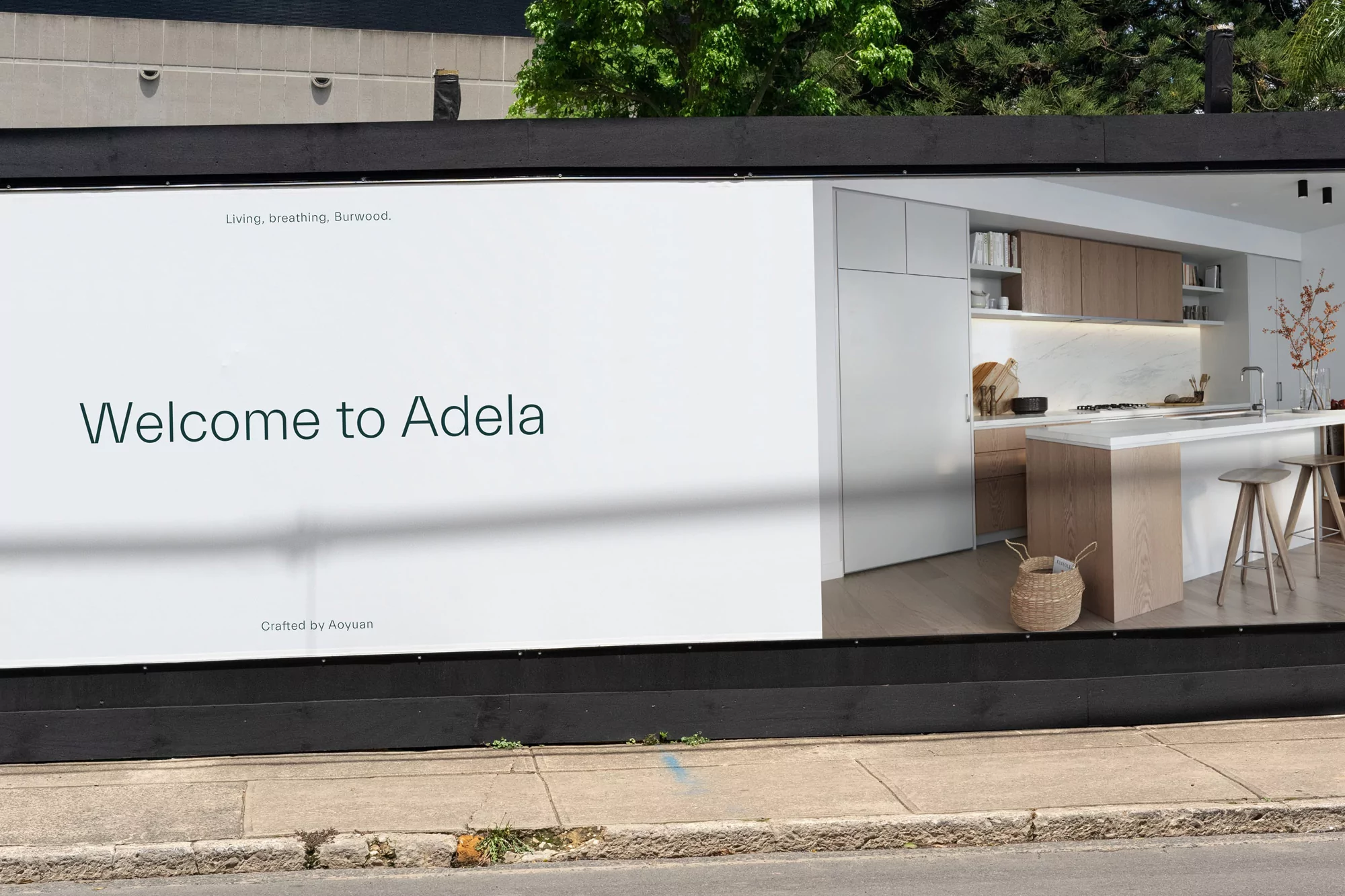 Billboard advertisement featuring a modern kitchen design with white cabinets and a central island, promoting Adela.