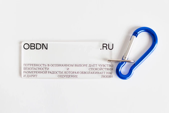 Promotional image featuring a transparent plastic tag with black text, a website address, and a short message, alongside a blue carabiner.