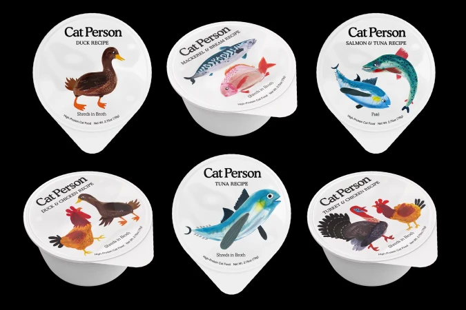 Variety of Cat Person cat food cups with different recipes like duck, tuna, and salmon, each with cartoon illustrations of ingredients.