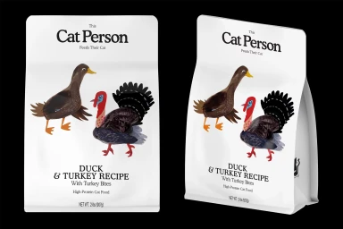 Two white Cat Person pet food bags featuring duck and turkey illustrations against a solid black background.