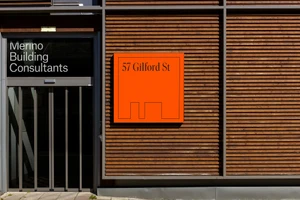 Exterior of Merino Building Consultants with wooden slat cladding and a bright orange sign reading 57 Gilford St.