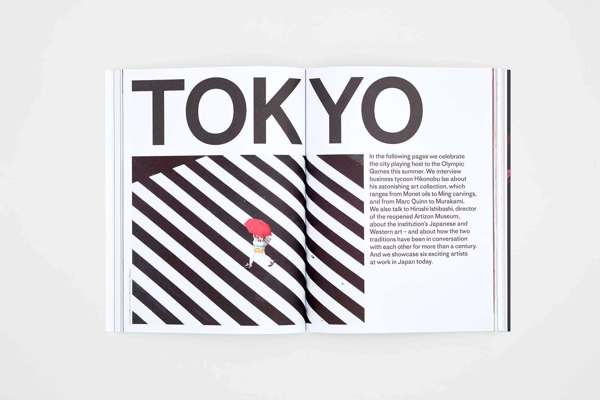 Open magazine spread featuring an image with diagonal black and white stripes and a woman with a red umbrella, and article text.