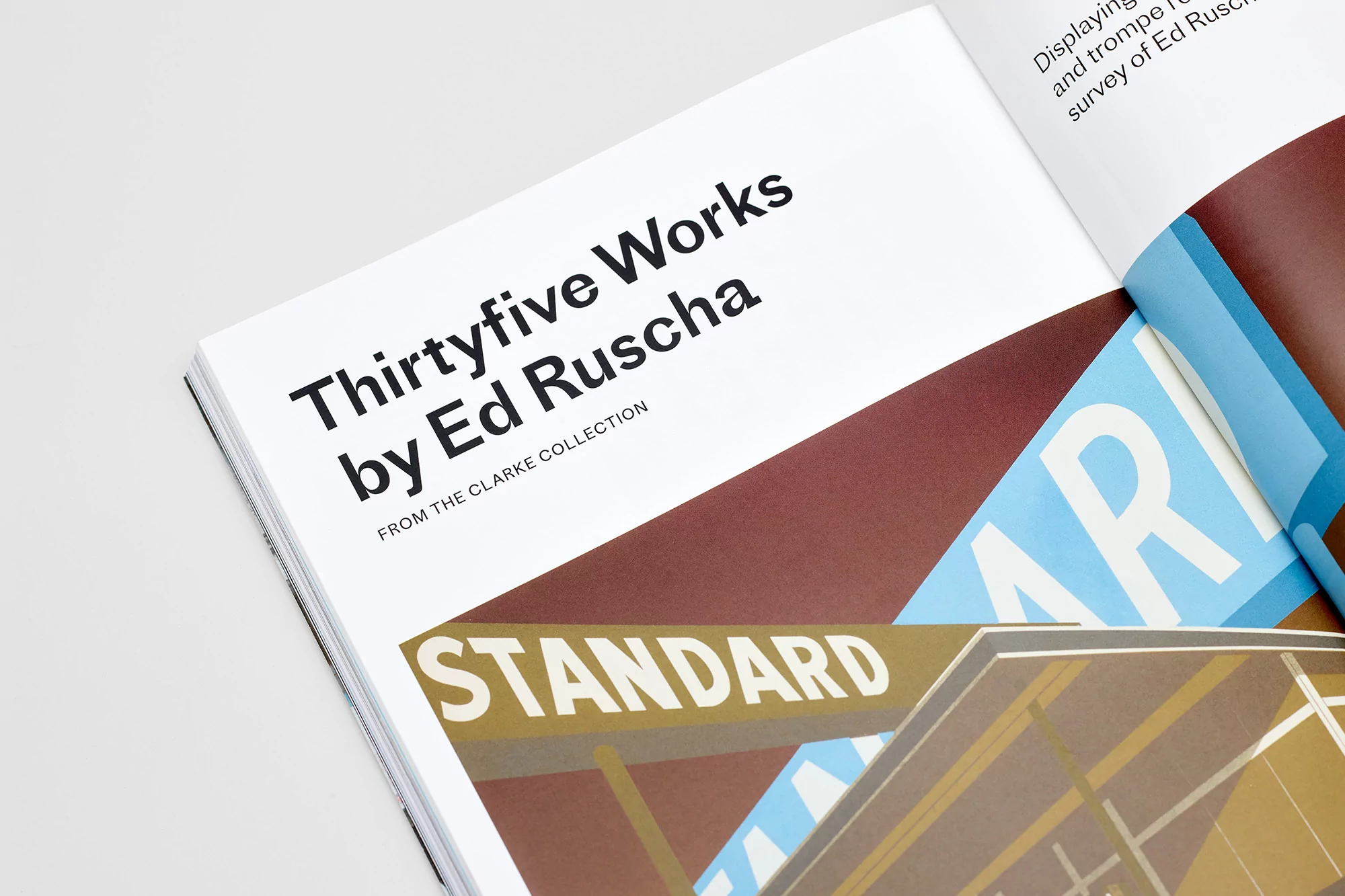 Open book displays 'Thirtyfive Works by Ed Ruscha' alongside art featuring a 'Standard' sign in earth tones and blue hues.