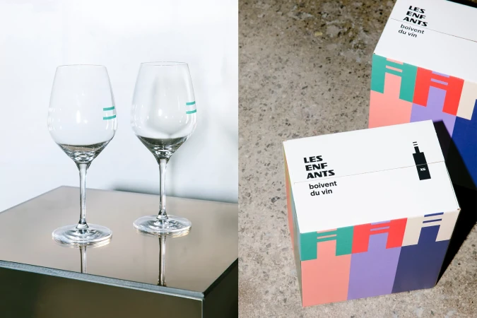 Two elegant wine glasses with teal accents sit on a sleek table beside gift boxes with bold geometric designs and modern typography.