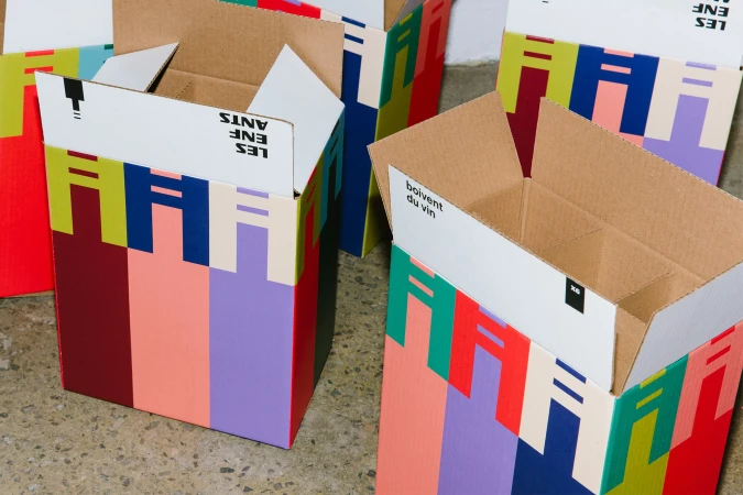 Colorful cardboard boxes with abstract designs, arranged on a speckled surface, present a visually appealing and eco-friendly aesthetic.