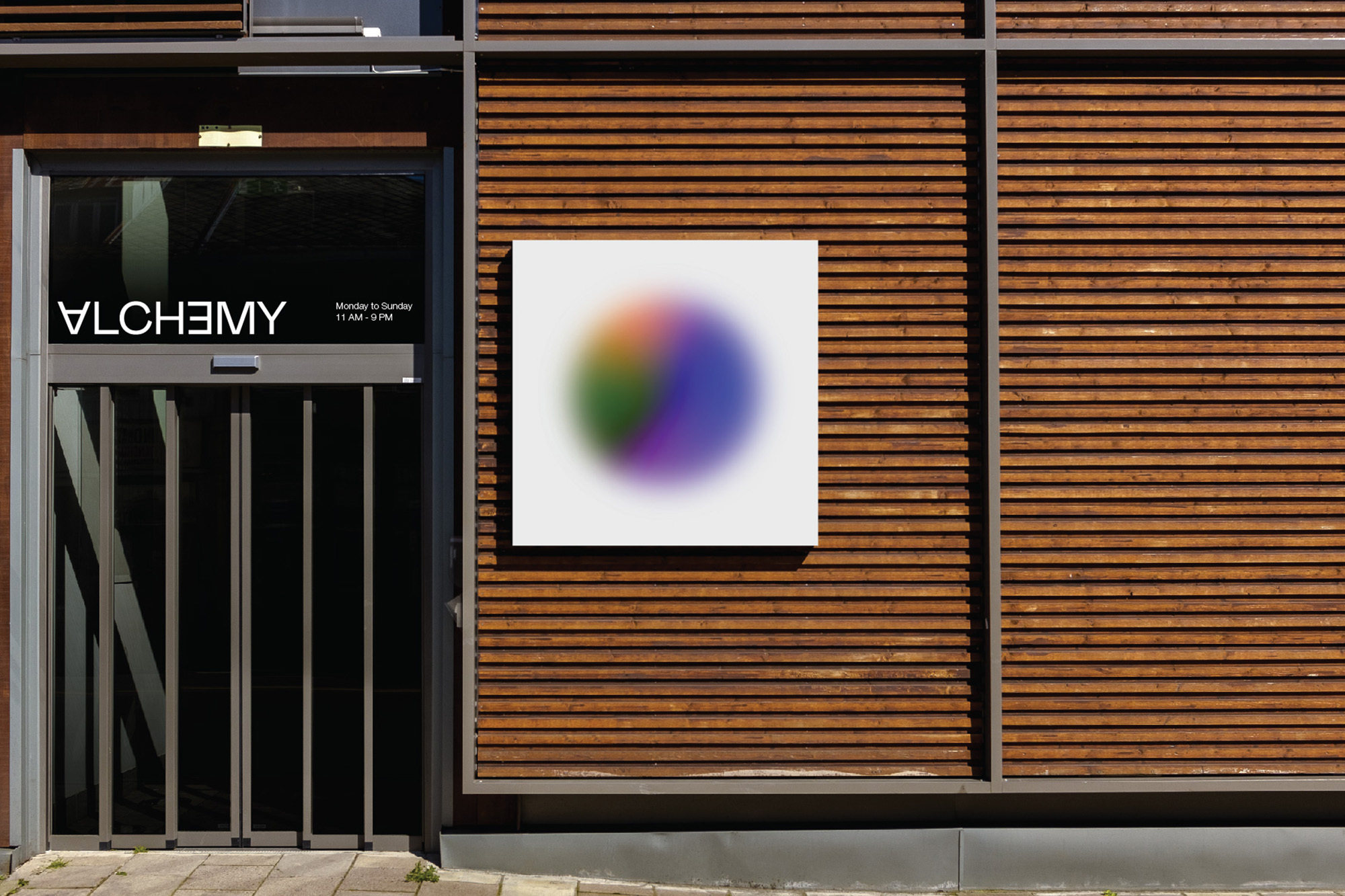 Exterior shot of a modern building with wooden siding and an abstract art piece next to the doorway entrance.