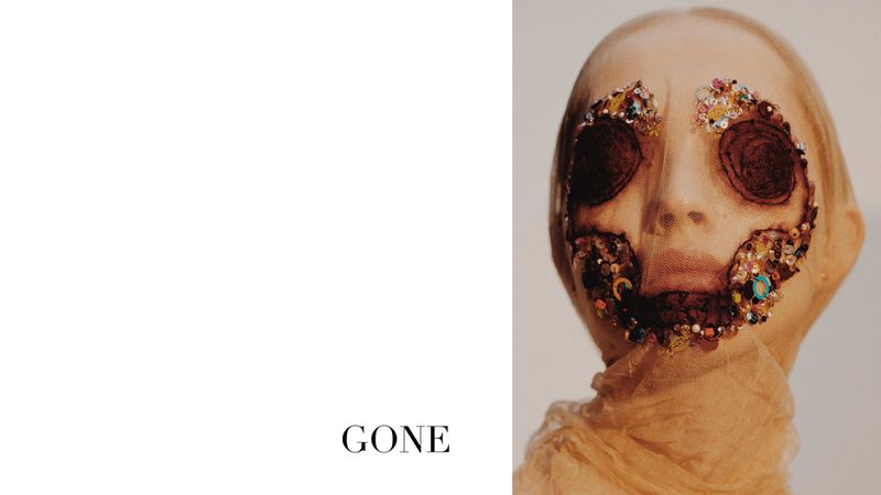 Portrait of person with elaborate, decorative covering over face, light neutral studio backdrop, fashion-forward, conceptual, beauty editorial.