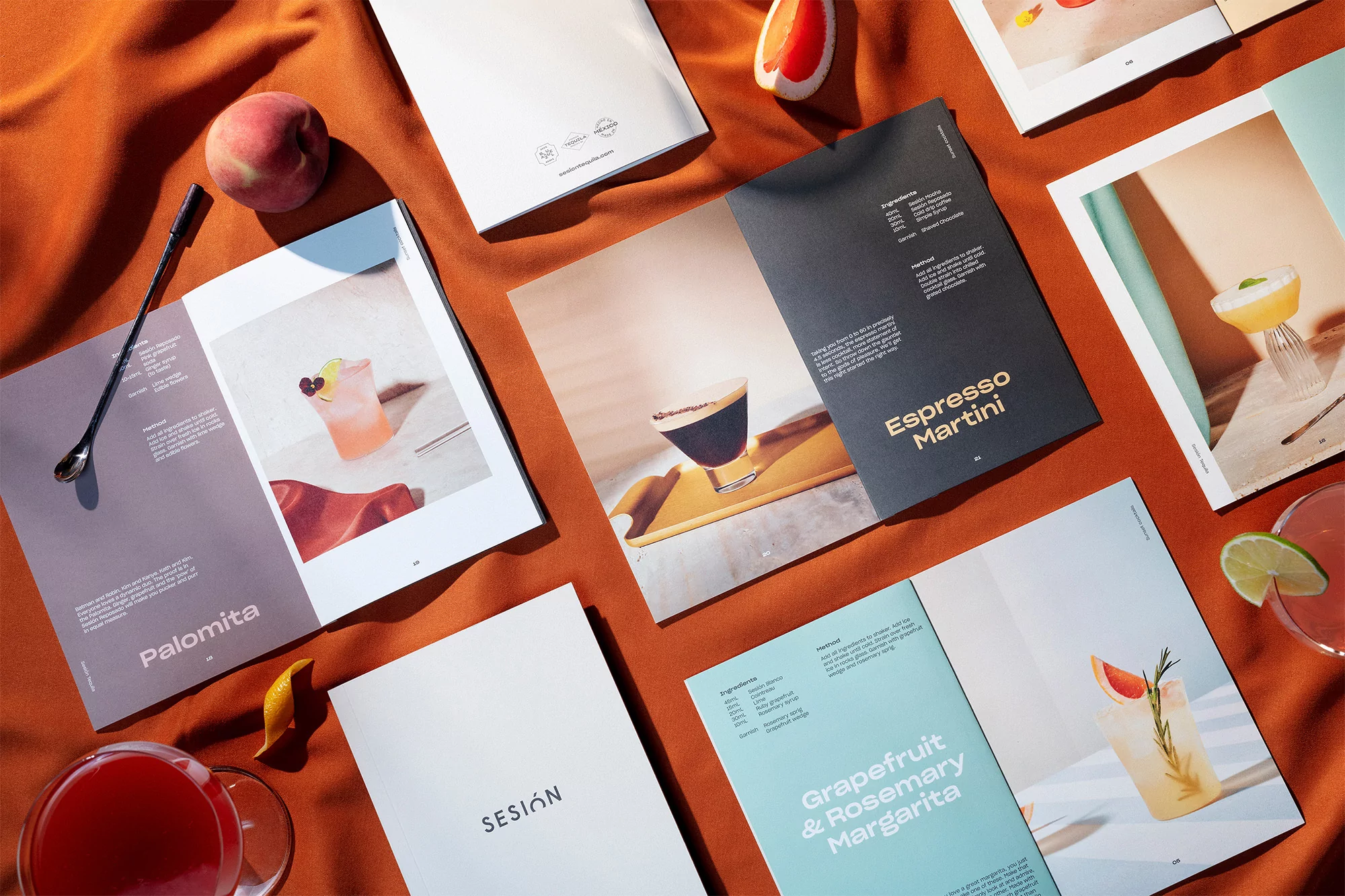 Overhead shot of cocktail recipe book and drinks on orange cloth featuring drink names like Espresso Martini and Palomita.