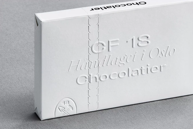 Close-up of a white chocolate box with embossed text, featuring the brand name 'Chocolatier' and minimalist design on a gray background.