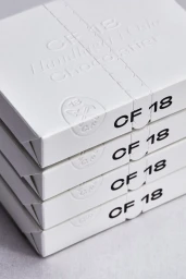 A stack of white CF18 Chocolatier packaging boxes with embossed branding and bold black typography on a clean neutral background.