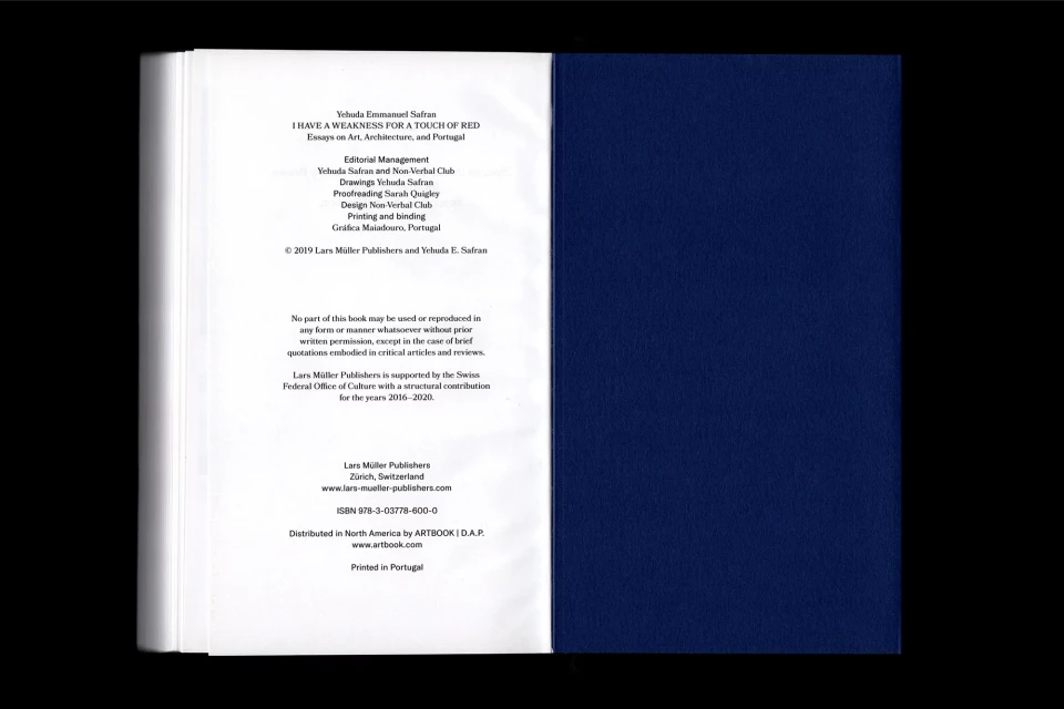 Open book featuring text and book cover displaying a solid dark blue on a black backdrop, focusing on design and publication elements.