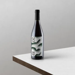 Wine bottle with modern white label featuring large green and black typography on a white surface