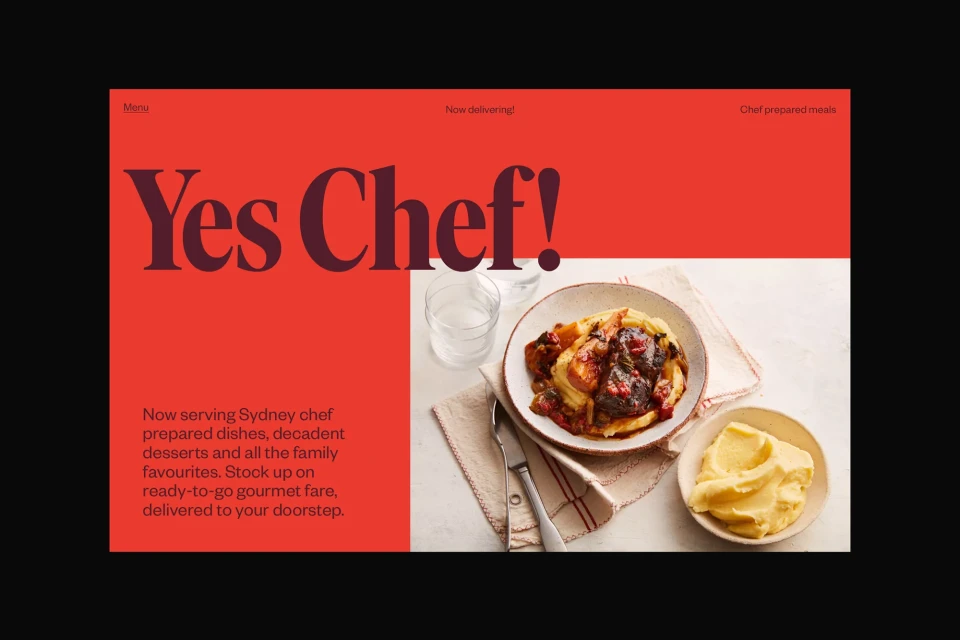 Overhead shot of chef prepared food on a plate, served with a glass of water and a dish of yellow sauce, over a red background.