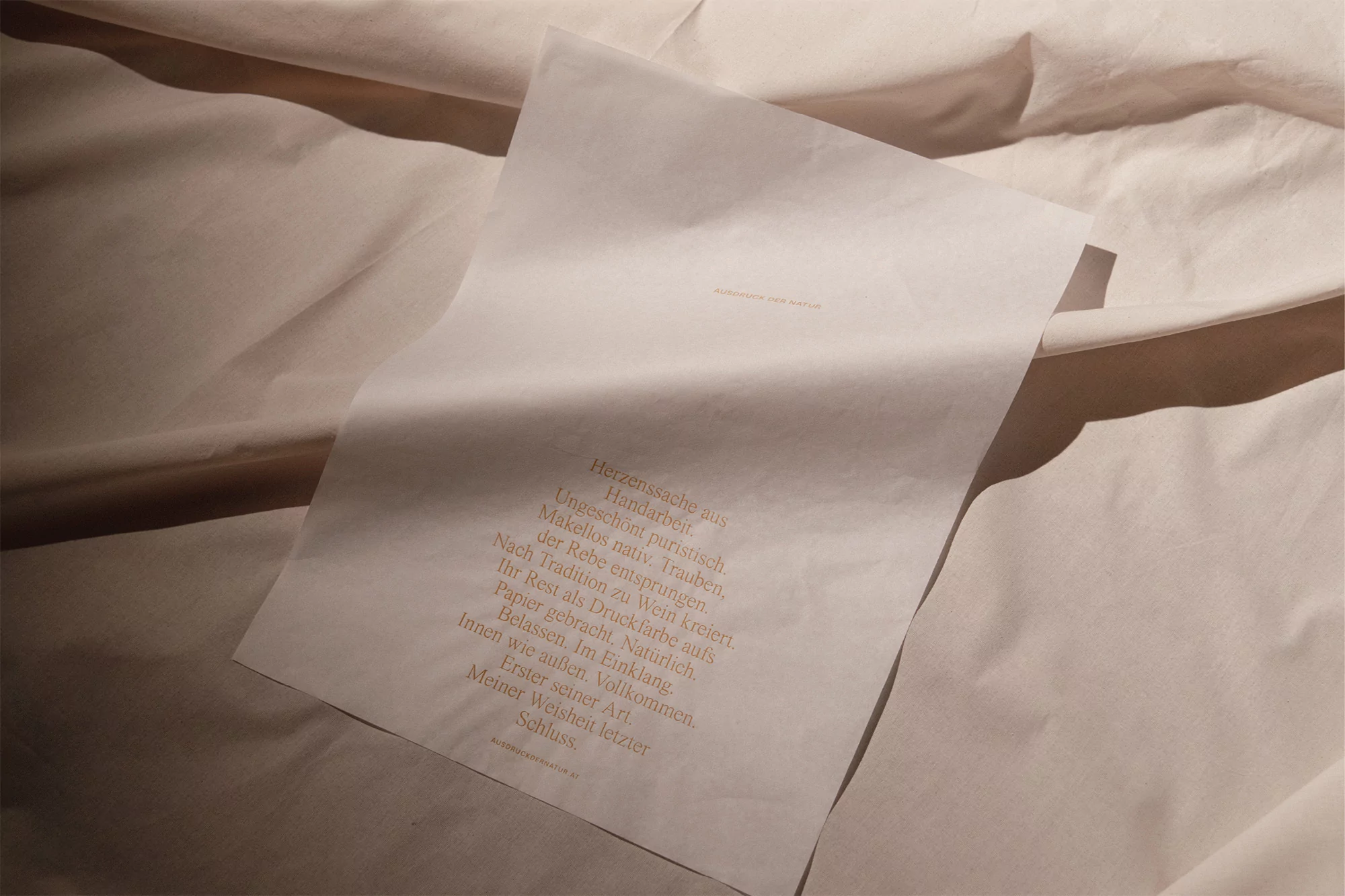 Cream-colored sheet of paper with German text on a cream-colored textile background, creating a soft, minimalist aesthetic.
