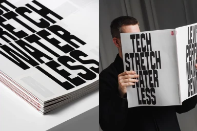 Man holding open a magazine featuring bold typography with tech stretch water less branding against a grey studio backdrop