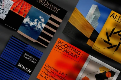 Flat lay arrangement of graphic design publications and brochures with bold typography and abstract imagery against a dark textured background