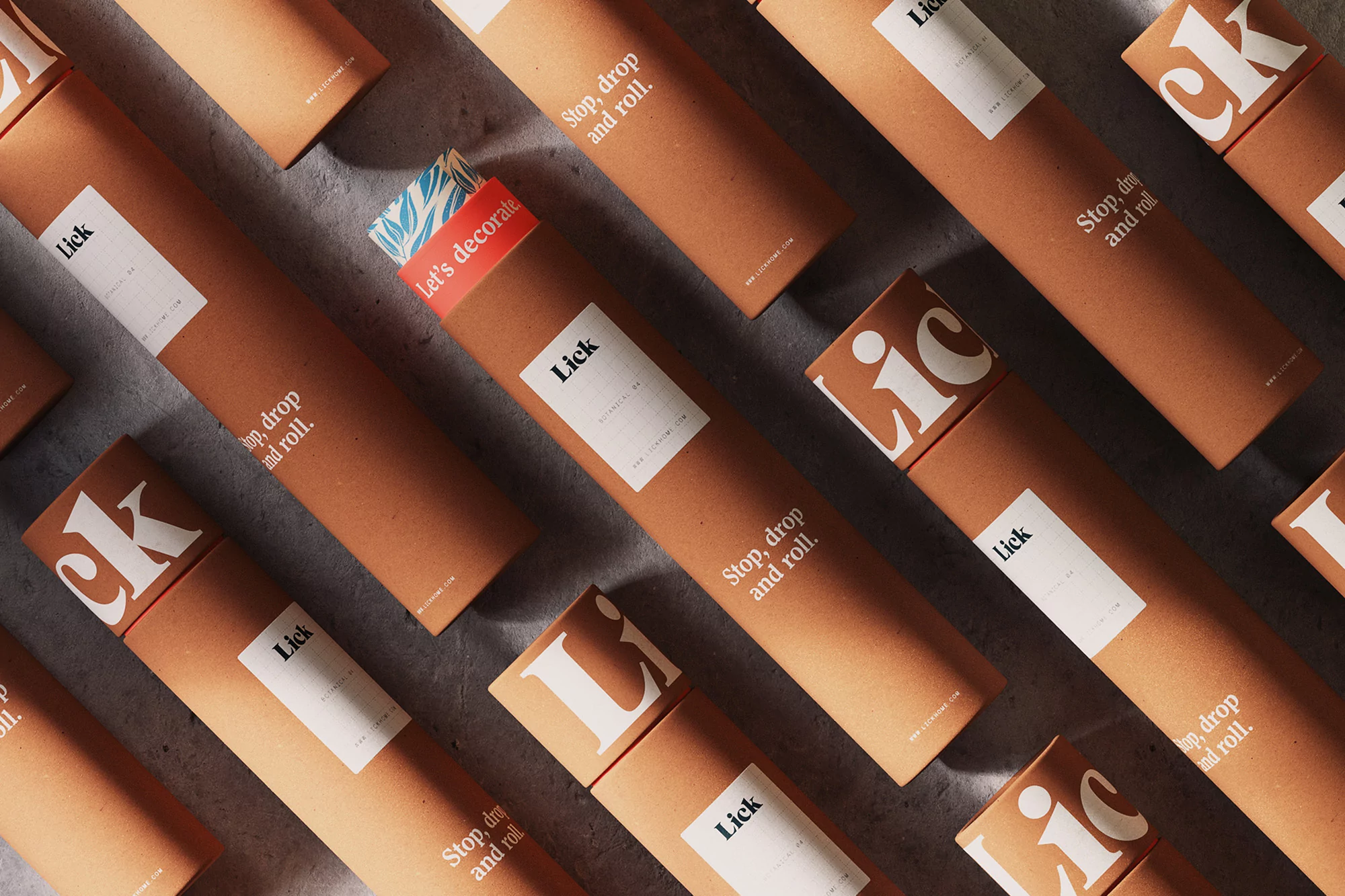 Multiple brown cardboard tubes with the brand name 'Lick' and white labels scattered across a textured gray surface, creating a pattern.